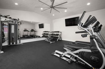 A gym with a variety of equipment including treadmills, elliptical machines, and a weight machine.